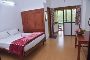 A bedroom with a bed, wooden wardrobe, and a view through a glass door to an outdoor area.