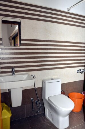 Une salle de bain équipée d’un lavabo, de toilettes et d’un bidet, ainsi qu’un miroir au-dessus du lavabo.