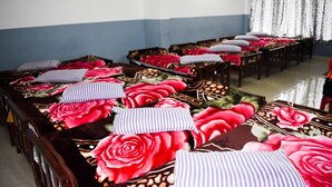 Habitación de hotel con varias camas, cada una con ropa de cama floral y almohadas a rayas.