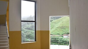 Una habitación con un ventanal grande, una escalera y vistas a un paisaje verde.