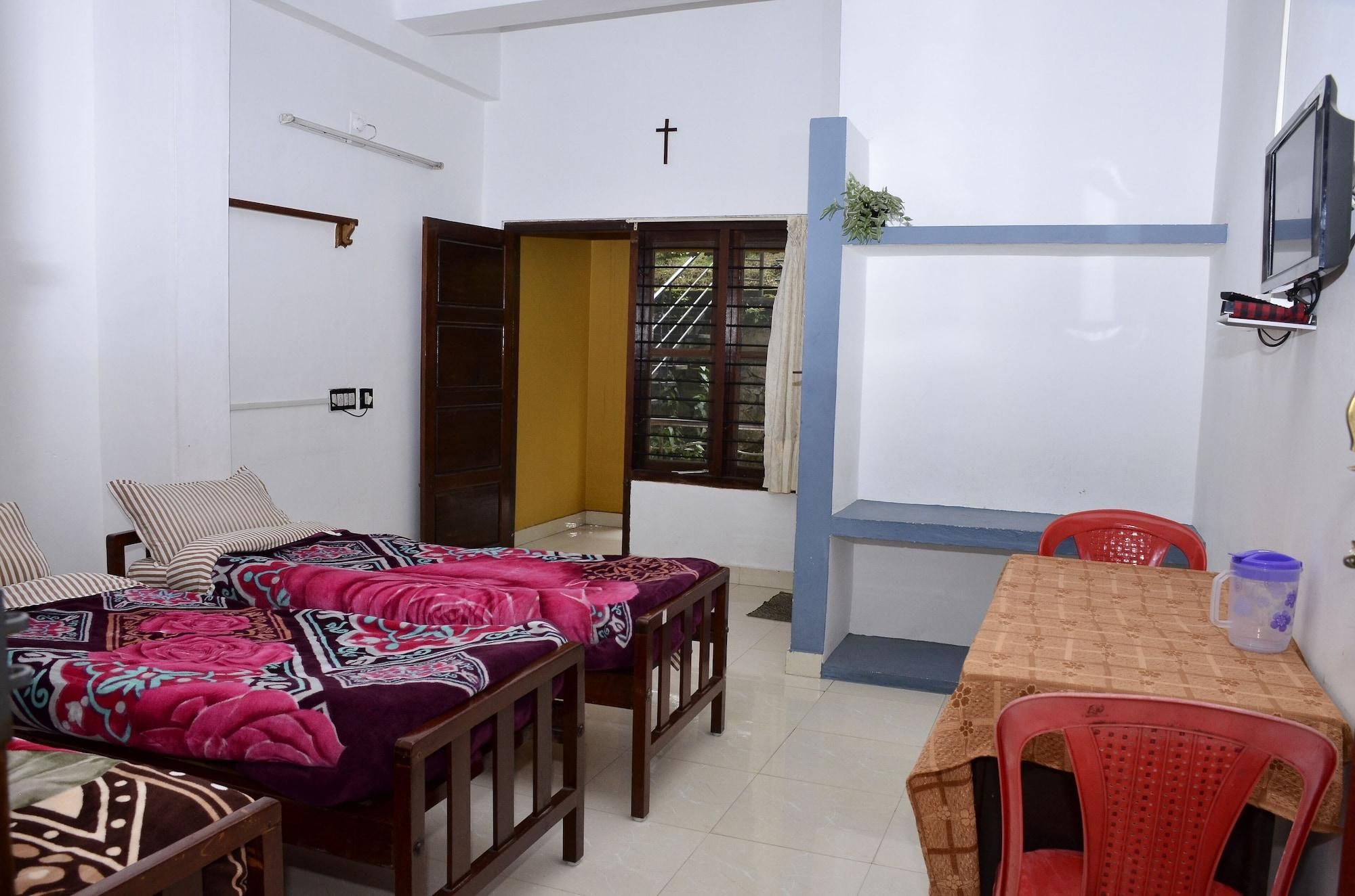 A room with a bed, a desk, a chair, a window with a view, and a cross on the wall.