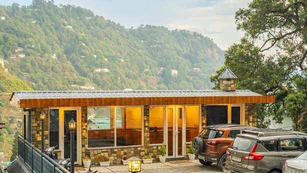 Een modern gebouw met een gevel van steen, grote ramen en een balkon met hekwerk.