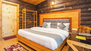 A log cabin bedroom with a wooden bed, a wooden wardrobe, and a small table. - Hotel Winterfell Mussoorie (Dehradun)
