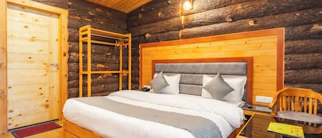 A log cabin bedroom with a wooden bed, a wooden wardrobe, and a small table.