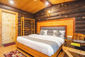 A log cabin bedroom with a wooden bed, a wooden wardrobe, and a small table. - Hotel Winterfell Mussoorie (Dehradun)
