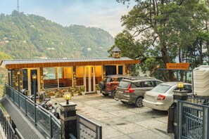 A lodge with a stone facade, a covered entrance, and a view of a mountainous landscape. - Hotel Winterfell Mussoorie (Dehradun)
