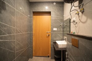 A bathroom with a wooden door, a sink, and a shower area. - Hotel Winterfell Mussoorie (Dehradun)