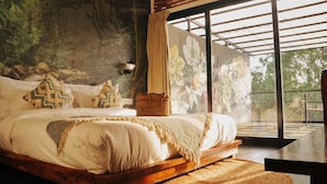 A bed with a wooden frame, a woven rug, and a painting of flowers on the wall. - Fabhotel Prime Amazonika Boutique Resort (Arpora)