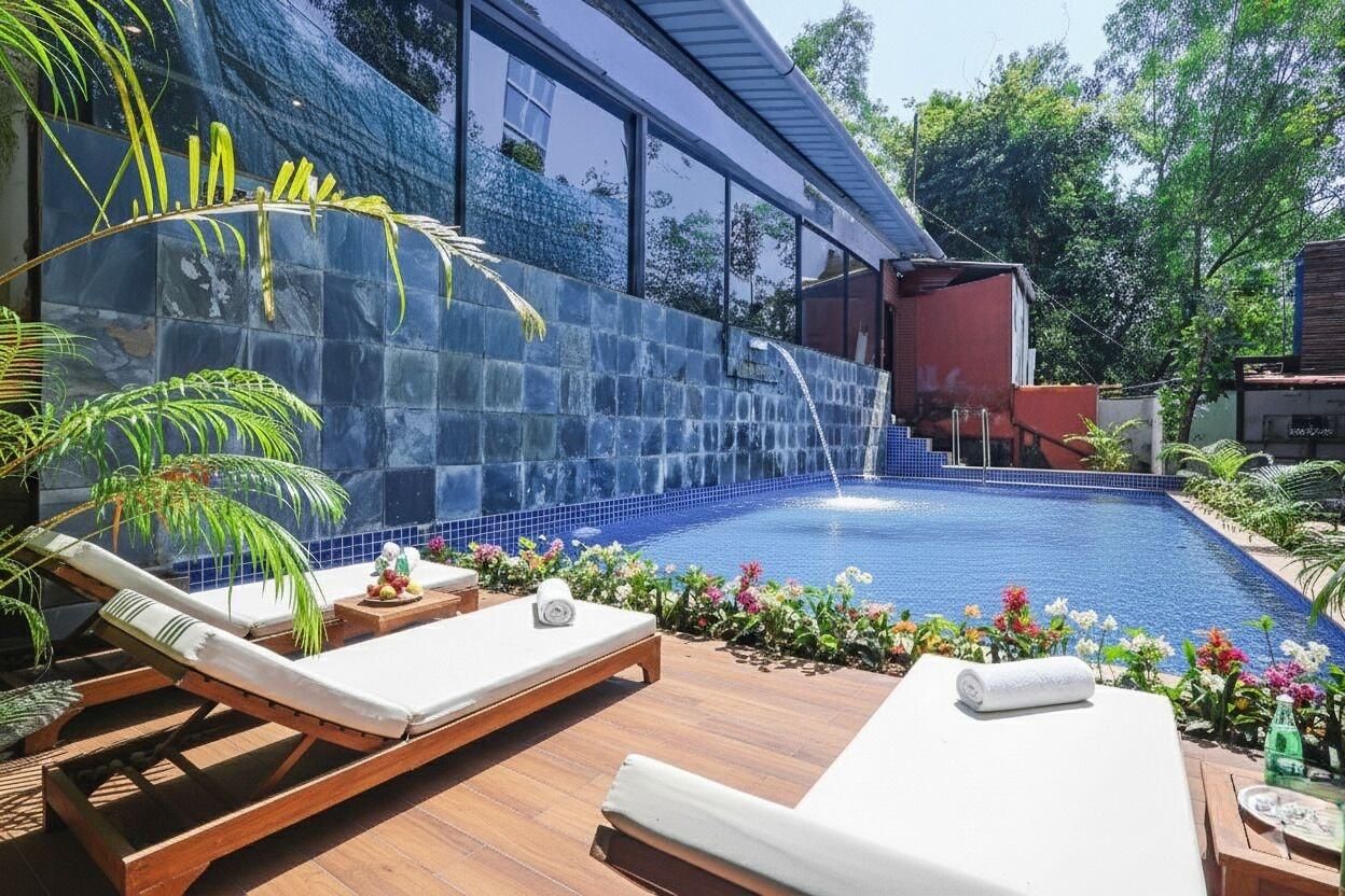 Une piscine agrémentée d’une cascade, de chaises longues et de plantes tropicales.