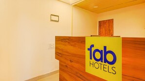 A reception desk with a wooden finish and a yellow sign that reads 'fab HOTELS'. - Fabhotel Prime Amazonika Boutique Resort (Arpora)