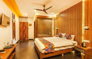 A modern hotel room with a large bed, a desk, a shower area, and a ceiling fan. - Fabhotel Prime Amazonika Boutique Resort (Arpora)