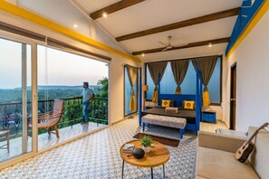 A spacious balcony with a view, a cozy sitting area with a sofa and a coffee table, and a bed with curtains. - Fabhotel Prime Amazonika Boutique Resort (Arpora)