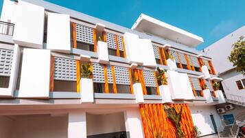 A modern multi-story building with balconies, a staircase, and a covered entrance area.