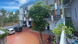A multi-story building with a tiled parking area, a tree in the foreground, and a clear sky. - Ngochoa Hotel (Da Nang Municipality)
