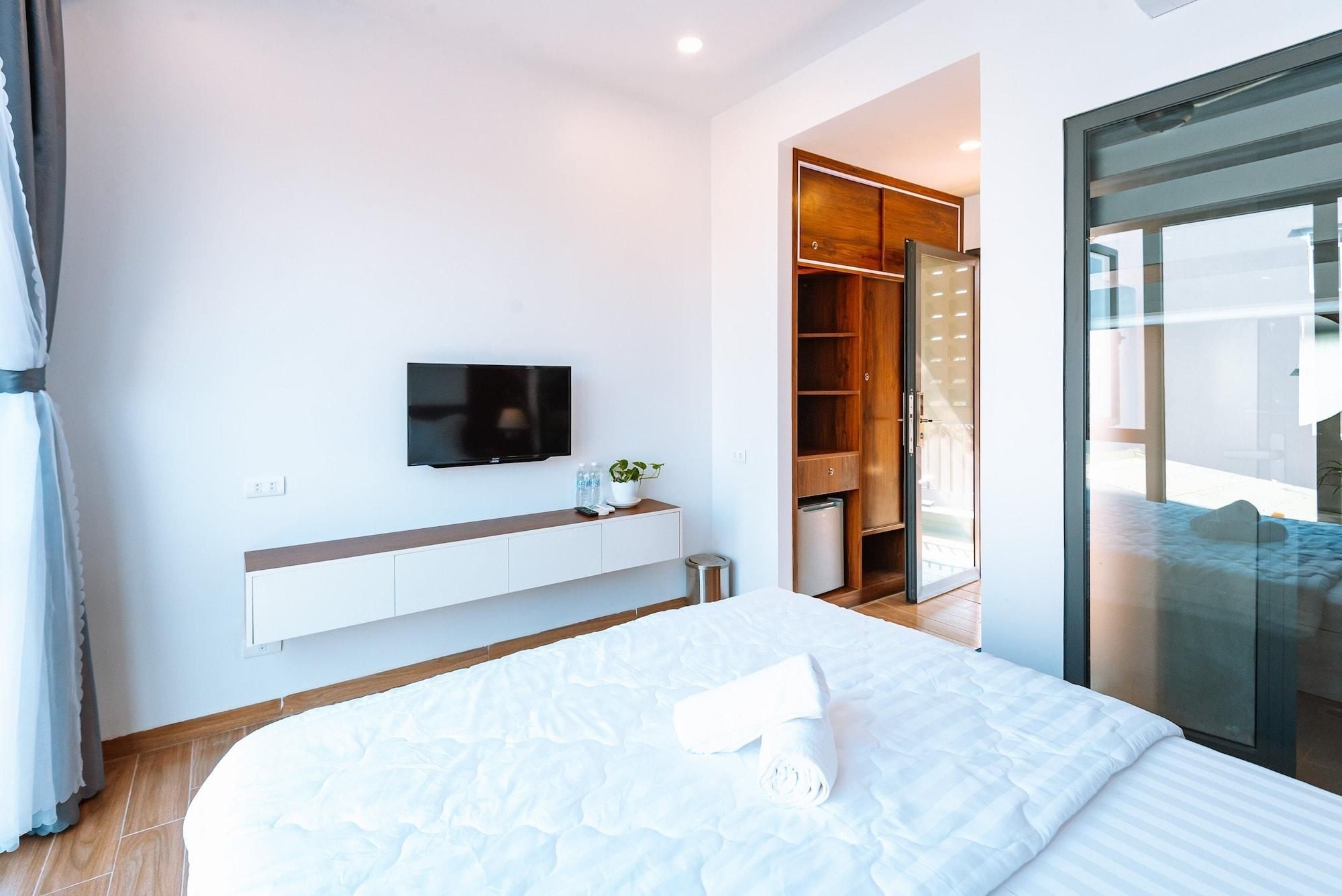 A modern bedroom with a bed, a TV, a wardrobe, and a sliding glass door to a balcony.