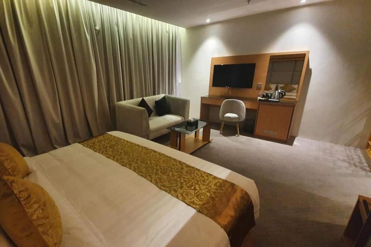 A hotel room with a bed, a desk, a chair, a television, and a wardrobe.