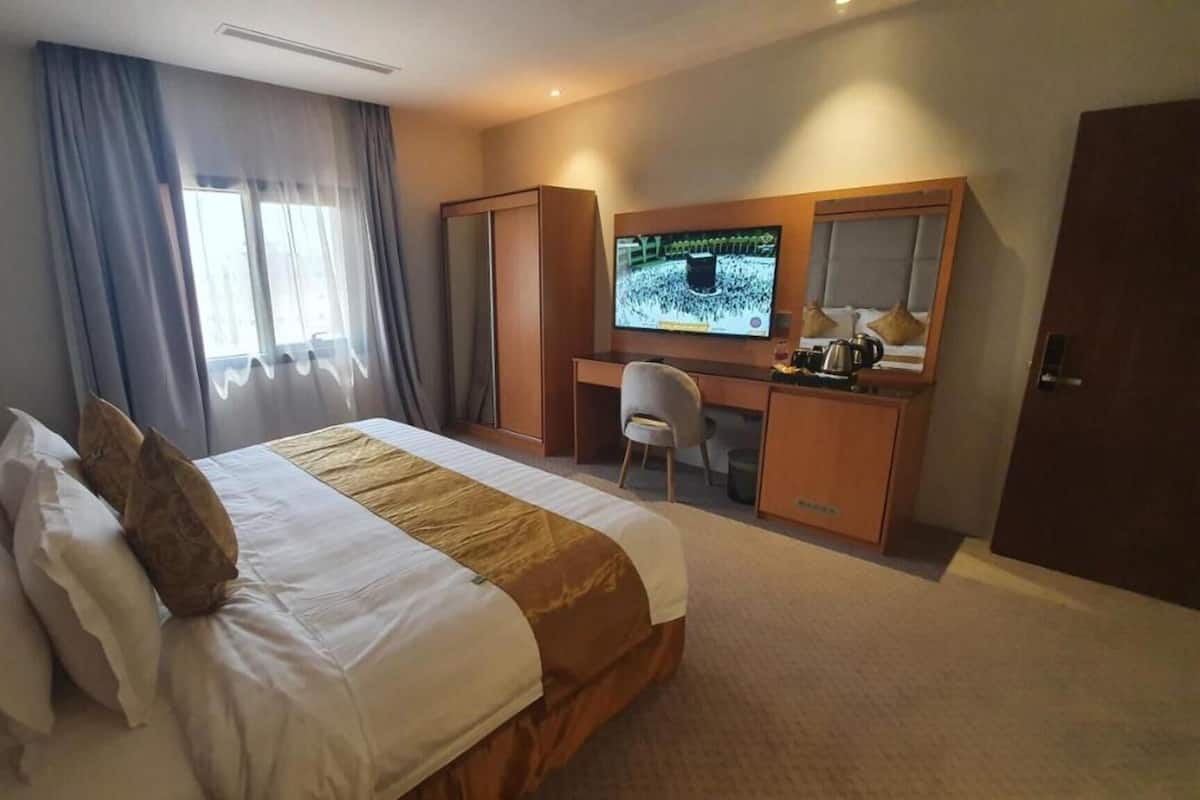 A hotel room with a bed, a desk, a television, and a wardrobe.