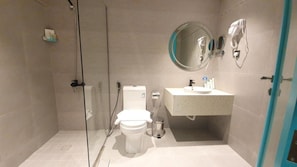 A bathroom with a glass-enclosed shower, a toilet, a sink with a mirror, and a towel rack. - Al Rayan Hotel (Jeddah)