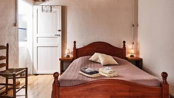 A wooden four-poster bed with a headboard, two bedside lamps, and a folded towel on the bed.