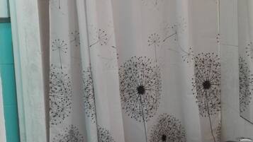 A bathroom with a shower curtain featuring a dandelion pattern, a white sink, and a mirror.