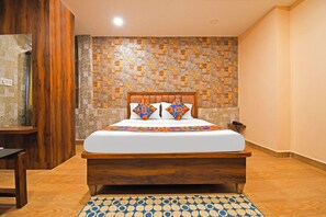 A hotel room with a wooden bed, a patterned wall, and a blue and white patterned rug.