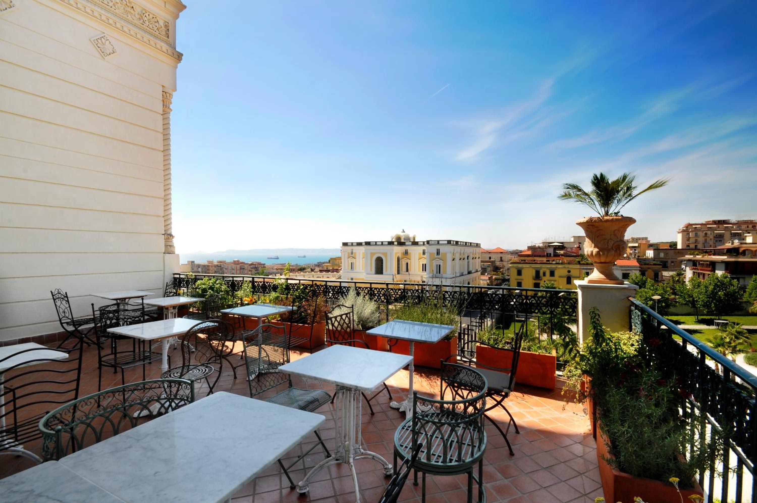 Um terraço com área de estar externa, vista para a cidade e um vaso decorativo grande.