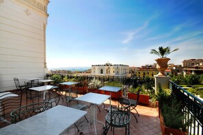 A terrace with outdoor seating, a view of the city, and a large decorative pot. - Villa Battista (Ercolano)