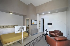 A hotel room with a bed, a desk, a chair, a standing lamp, and a door leading to a bathroom. - Villa Battista (Ercolano)