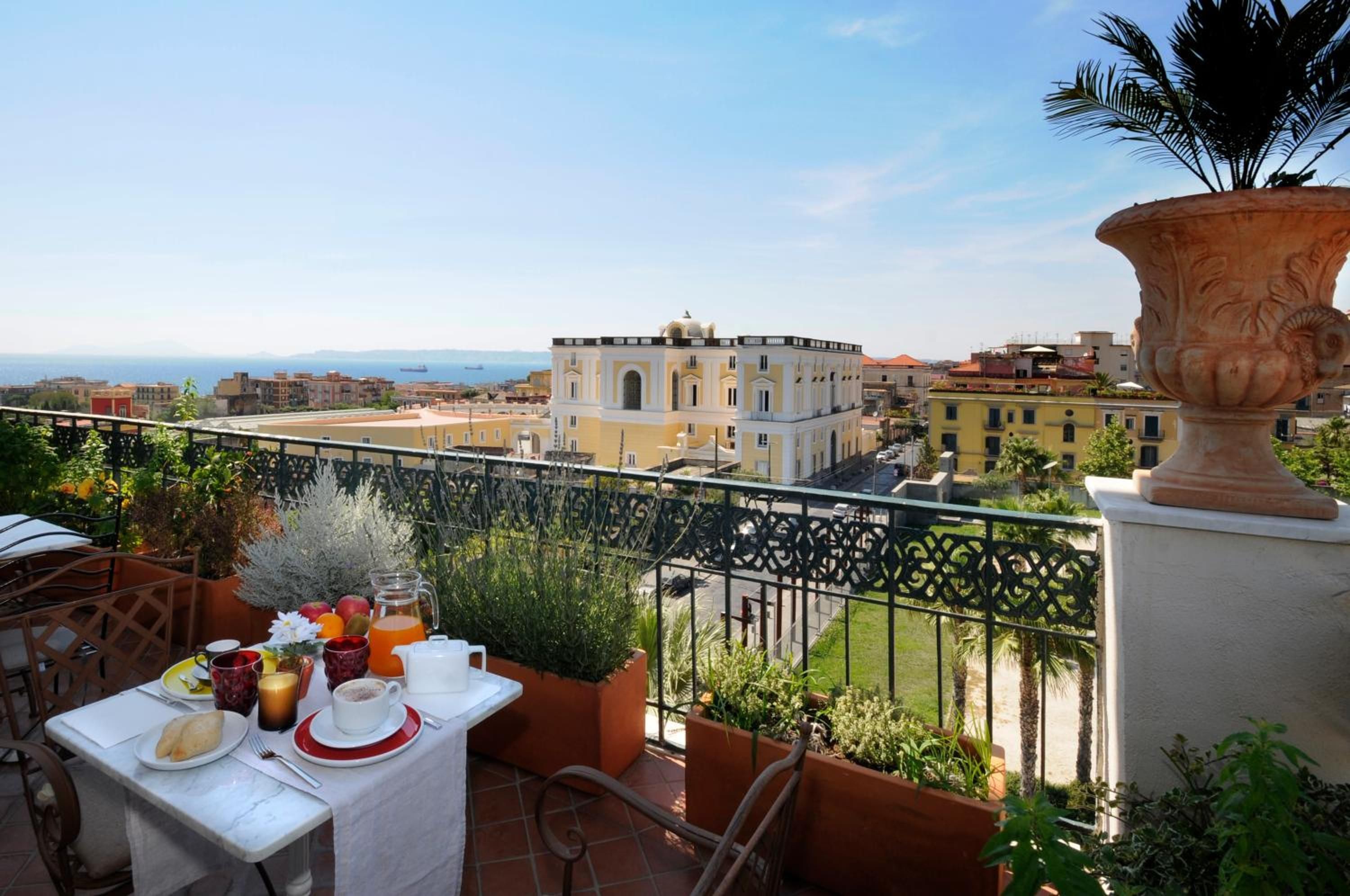 Un balcon avec une table préparée pour le petit-déjeuner, offrant une vue sur le paysage urbain de la côte.