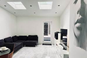 Uma sala de estar moderna com um sofá seccional, uma TV de tela plana e um claraboia.