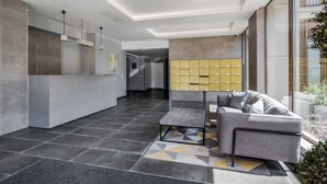 Un hall d’entrée moderne comprenant un comptoir d’accueil, un canapé, un tapis à motifs et une rangée de casiers.