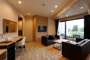 Una sala moderna con televisor de pantalla plana, un escritorio de madera, un sofá y un balcón con vistas.