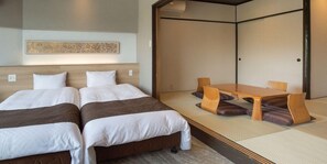 Habitación de hotel con dos camas, una zona de estar con esterilla de tatami y un tradicional puertas correderas.