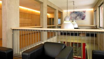 A modern interior with a high ceiling, a mezzanine level, and a view of the outside.