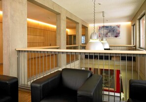 Ein modernes Interieur mit hoher Decke, einer Galerie und Blick ins Freie.