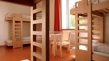 A room with bunk beds, a table, and chairs.