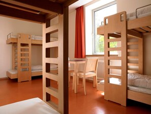 Ein Zimmer mit Etagenbetten, einem Tisch und St ühlen.