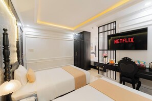 A hotel room with two beds, a desk, a TV, and a wardrobe. - Elegant Hotel (Xuan Huong - Da Lat)