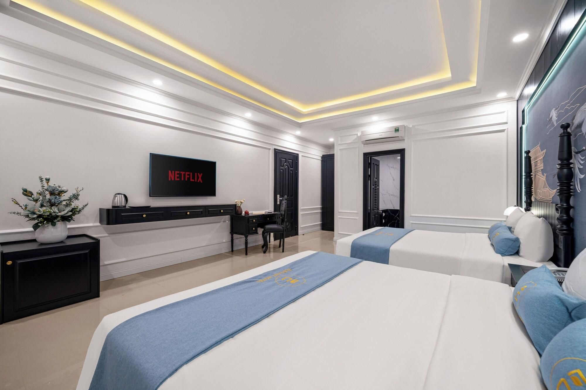 A hotel room with a bed, a desk, a chair, a TV, and a decorative wall.