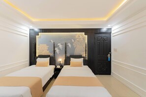 A hotel room with two beds, a wall mural, a door, and a nightstand with a lamp. - Elegant Hotel (Xuan Huong - Da Lat)