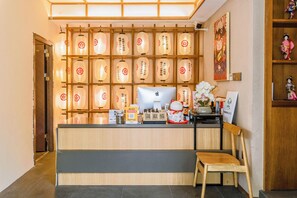 A reception area with a wooden desk, a computer, and traditional Japanese lanterns on the wall. - Shenzhen Yusu Linting Inn (Shenzhen)
