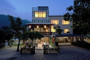 A modern hotel with a two-story structure, a covered outdoor seating area, and a view of the surrounding landscape. - Shenzhen Yusu Linting Inn (Shenzhen)