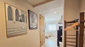 Un pasillo con piso de madera, un perchero y dos cuadros en la pared.