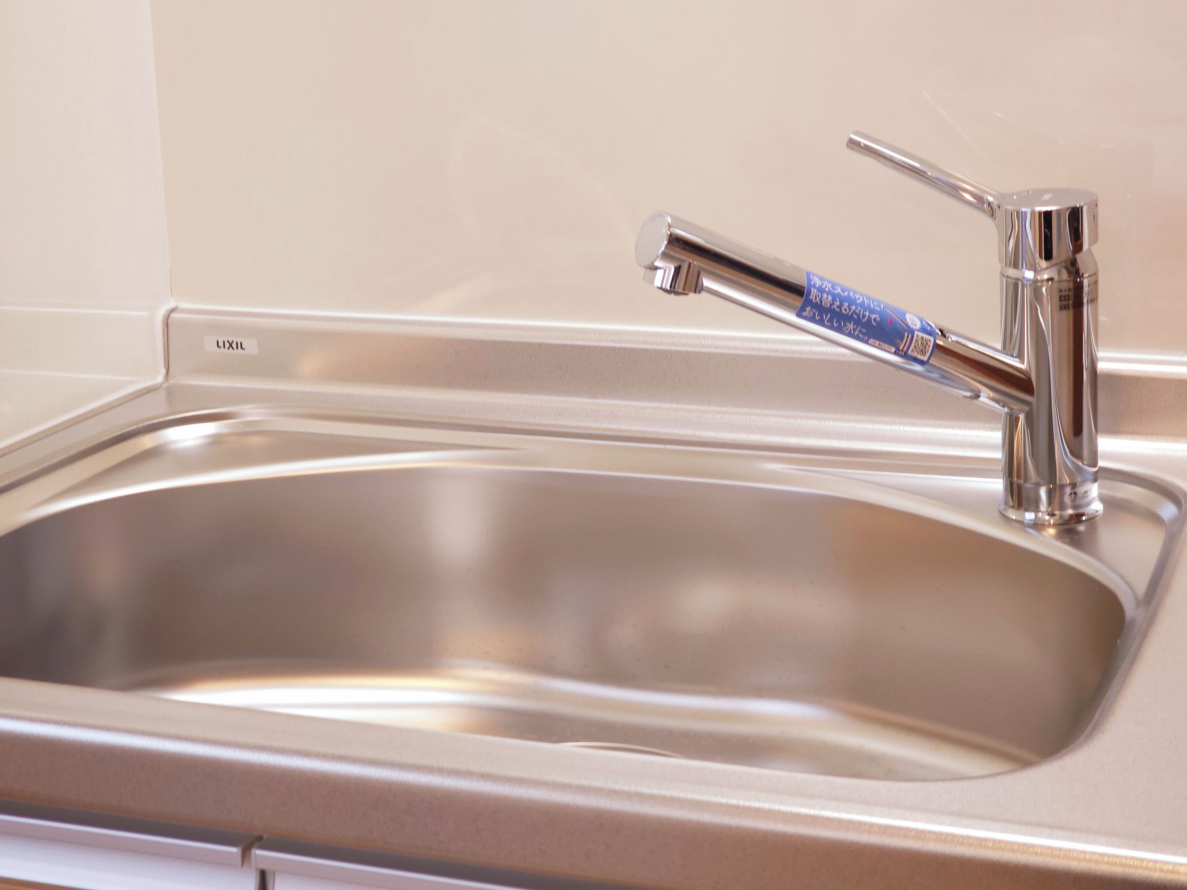 A stainless steel sink with a chrome faucet and a soap dispenser.
