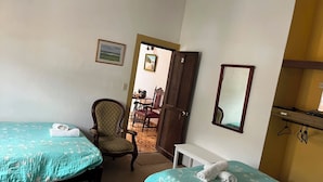 Ein Hotelzimmer mit zwei Betten, einem Sessel, einem Schreibtisch und einem Spiegel.