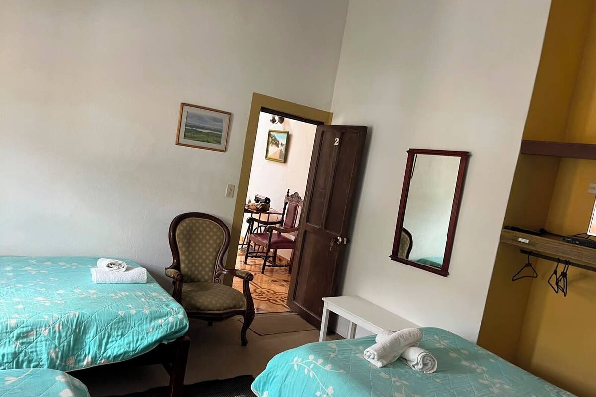 Una habitación de hotel con dos camas, una silla, un escritorio y un espejo.