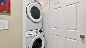 A laundry area with stacked washers and dryers, a door, and a light switch.
