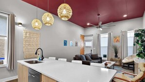 Una cocina moderna con una isla central, un rincón comedor con sofá y un ventilador de techo.