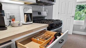 Una cocina con cafetera, estufa y organizador de cajones.