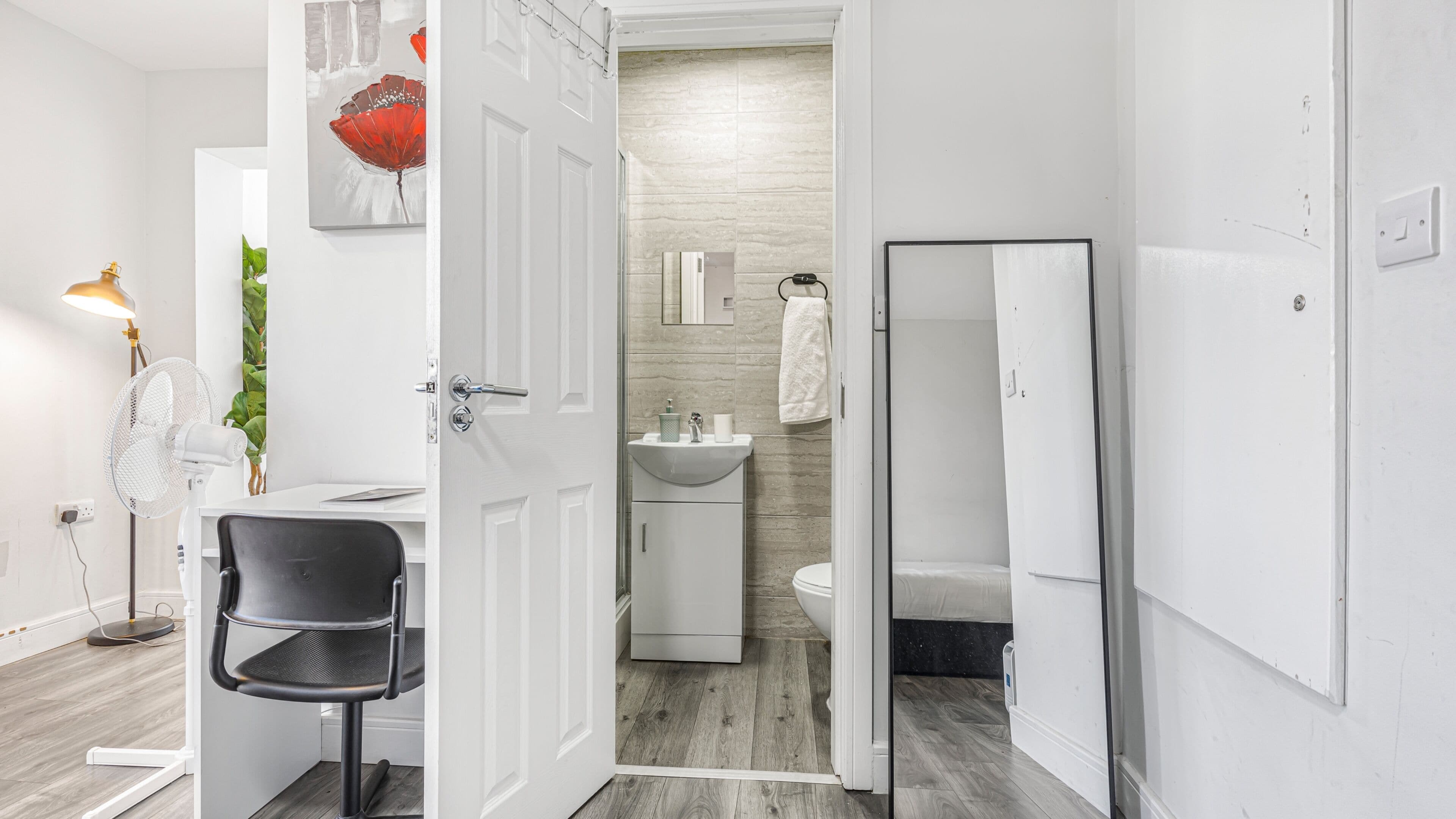 A modern hotel room with a desk, chair, and a bathroom with a toilet and sink.